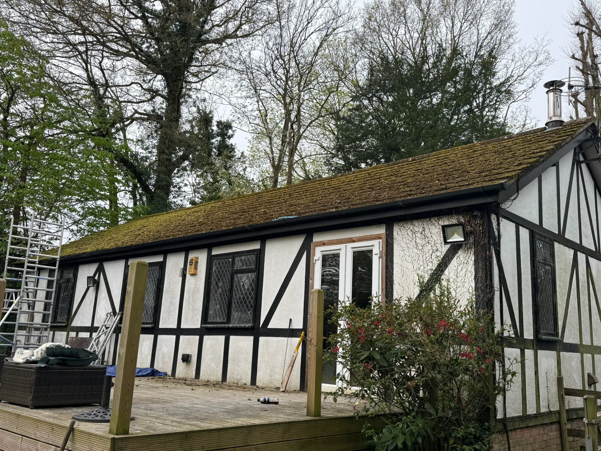 Tudor cottage with moss-covered roof before cleaning